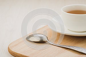 white cup of tea and spoon on a wooden tray/white cup of tea and spoon on a wooden tray on a wooden background. Copy space