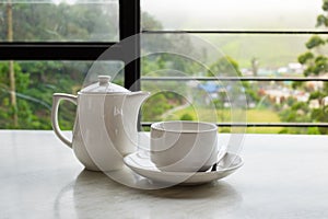 White cup of tea and teapot on white marble table
