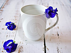 White cup of tea with violet flowers on wooden background ,cup of coffee empty pigeonwings, Clitoria ternatea, bluebellvine butter