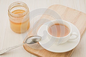 white Cup of tea on a wooden tray and jar of honey/white Cup of tea on a wooden tray and jar of honey. Selective focus