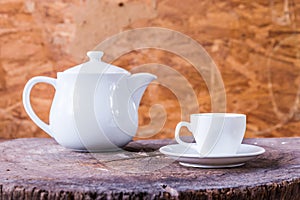 White cup with white tea pot on wood background