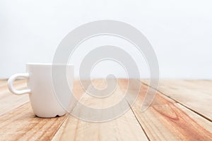 White cup on wooden table and cement wall background,Soft focus