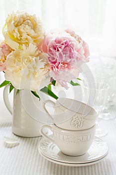 White cups and a bouquet of peonies