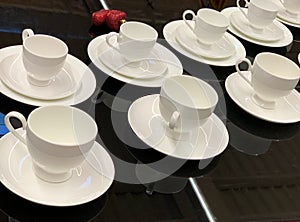 White cups with saucer standing on table.