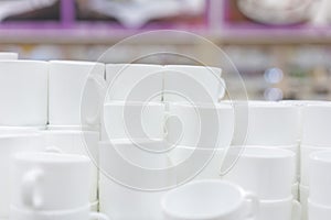 White cups on the shelf in the store. White ceramic coffee cups and saucers on shelves. Shelves with kitchen utensils