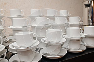 White cups for tea piled on table with plates for coffee-break