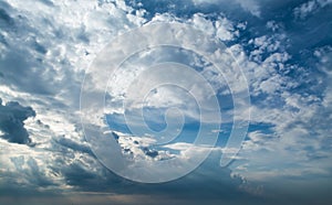 White curly clouds in a blue sky with dark clouds. Sky background.