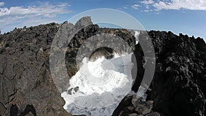 White curly foamy wave at rocks rocky canyon on Reunion island.