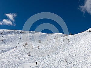 White curves on ski slopes and blue sky with clouds