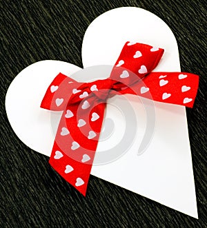 White cut out paper heart with red ribbon bow with hearts.