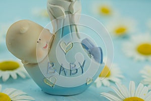 White daisy flower on blue background with baby boy statue