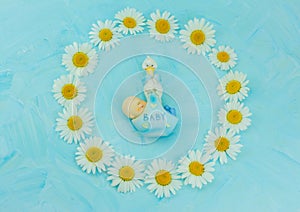 White daisy flower on blue background with baby boy statue