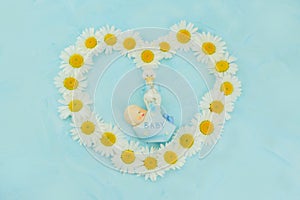 White daisy flower on blue background with baby boy statue