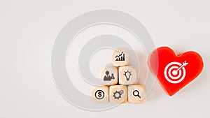 White dartboard sign on red heart and pyramid of business icon on wood cubes with copy space, brainstorming, target, goal concept