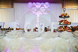 White decorations at the wedding reception. Arch and table with paper flowers