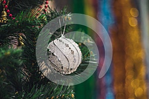 White decorative ball on the christmas tree on glitter bokeh background with blurred colorful background. Merry christmas card.