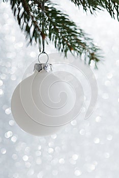 White decorative ball on the xmas tree on glitter bokeh background. Merry christmas card.