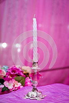 White decorative candles pink backgrounds . Beautiful candle on pink background . Candle in candlestick burning . Retro Candelabra