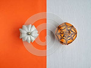 White decorative pumpkin and halloween donut on white and orange background