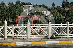 White decorative wooden fence near the concrete curb and gray asphalt road
