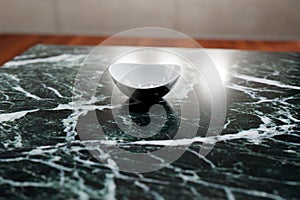 White deep small plate on a dark marble table surface in the kitchen