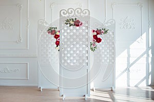 White delicate decorative wood panel in classical interior. Boudoir wedding room. Retro folding screen with flowers