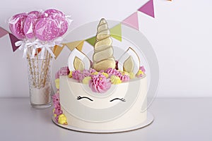 White delicate unicorn cake with pink lollipops on a white background