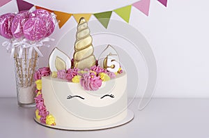 White delicate unicorn cake with pink lollipops on a white background