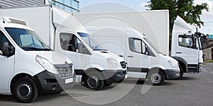 White delivery service van trucks cars in front of factory warehouse