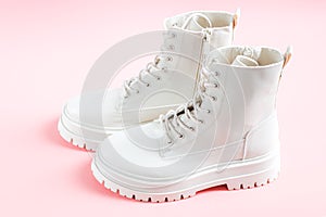White demi-season martens boots made of eco-leather with a rough sole stand on a pink.