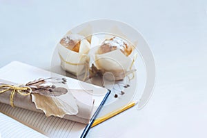 White desk table blank notebook with pencil and folded blank paper, decorated with dried flowers. Top view with copy spase. Still