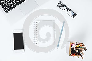 White desk top with smartphone and notepad