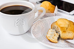 White desktop with cup of coffee, plate with muffin and smartphone, styled image for social media
