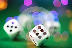 White dice on a green felt table with bokeh background