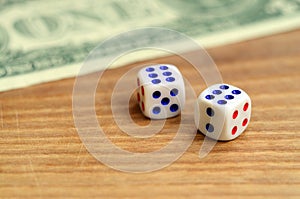 White dice are next to a dollar bill of US dollars on a wooden background. The concept of gambling with rates in monetary unit