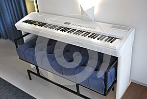 White digital piano keyboard and soft blue pouffe close-up