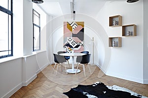 a white dining room with black chairs and a colorful art