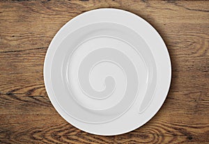 White dinner plate on wooden table top view