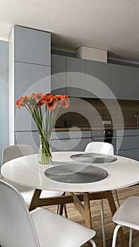 White dinning table in front of scandinavian kitchen, elegant nordic design and interior decor