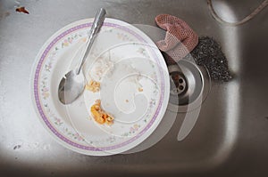 White dirty dish with spoon in sink after eating