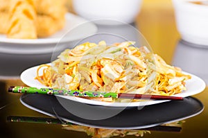 White dish with chinese food, noodles and vegetables. Chopsticks on the side