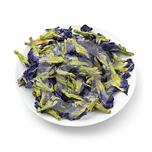 White dish with dried butterfly pea tea flowers close up on white background