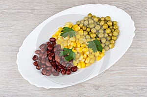 White dish with green peas, beans, sweet corn and parsley