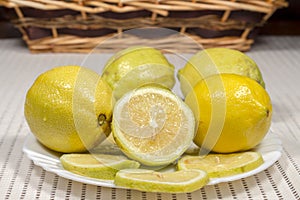 White dish with lemons with a wicker basket at background