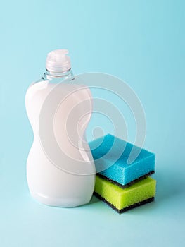 White dishwashing liquid in a plastic bottle and two foam sponges. Purity and household chemicals. Kitchen detergent on a pastel