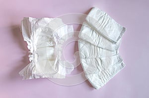 White disposable diapers for little babies on pink background. Top view, selective focus