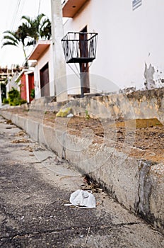 White disposable mask thrown on residential street next to trash