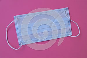 White Disposable Medical mask on the pink background the subject of personal virus protection