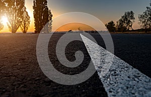 White dividing strip on an asphalt road. Highway. The road goes to the horizon. Sunset