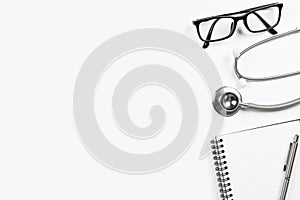 White doctor desk with stethoscope notebook with pen and eye glasses. Top view with copy space, flat lay